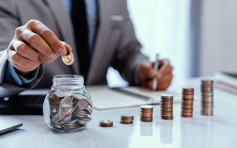 business man dropping money in jar reasonable rate of return in retirement
